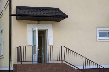 Yakın çekim açık havada detayını yeni anaokulu ya da bej renkli sıva duvarlar ile bina okul açmak beyaz giriş kapısı ve metal koruyucu basit ilkel kahverengi metal merdiven çit ve tutamaklar.