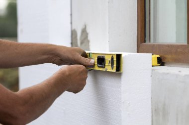 Alt düzey ve bıçak ölçme ve kesme beyaz sert poliüretan köpük levha yeni yüklenen Plastik pencere duvara eliyle. Modern teknoloji, yenileme, izolasyon kavramı.