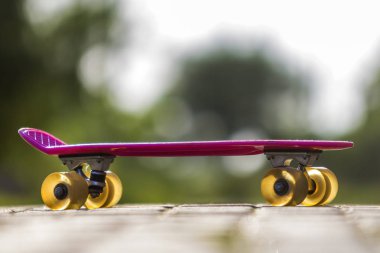 Yakın çekim çocuk plastik pembe parlak beyaz ve yeşil bulanık bokeh arka plan üzerinde izole kaldırım kaykay. Spor, eğlence, eğlenceli ve çalış kavramı.