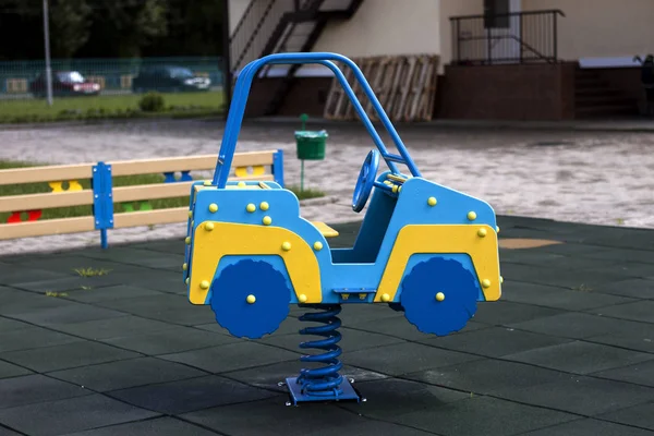 새로운 플라스틱 다채로운 파란색과 노란색 장난감 자동차 놀이터에 화창한 부드러운 — 스톡 사진