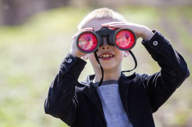 Dikkatle bir şey aracılığıyla dürbün uzaktan izlerken küçük sevimli yakışıklı tatlı sarışın çocuk portresi arka plan bulanık. Çocuk masumiyet, rüyalar, fanteziler ve hayal kavramı.