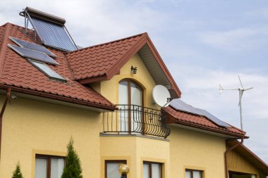 Yeni tugla ev kırmızı shingle çatı, uydu anteni, güneş panelleri ve parlak mavi gökyüzü arka plan üzerinde plastik tavan windows Close-up. Gayrimenkul ve profesyonelce yapılan iş kavramı.