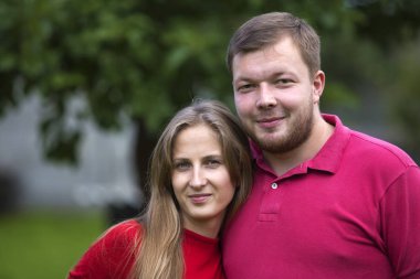 Yakın çekim Genç çekici mutlu romantik gülümseyen çift sevgi, sarışın uzun saçlı kız ve yakışıklı tıraşsız adam birlikte açık havada sarılma parlak güneşli arka plan bulanık üzerinde portresi.