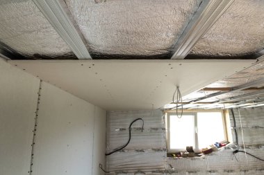 İnşaat ve tadilat yüklü küçük tavan penceresi, duvarlar ve tavan, elektrik telleri çıktı ve alçıpan gümüş alüminyum izolasyon folyo ile altında bitmemiş Oda detayını yakın çekim.