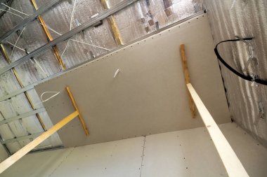 İnşaat ve tadilat gümüş alüminyum izolasyon folyo ile altında bitmemiş Oda görüş açısı duvarlar ve tavan ve alçıpan tahta çerçeveye bağlı. Yeniden yapılanma ve yenileme kavramı.