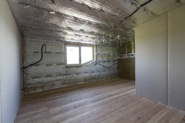 Büyük boş oda altında inşaat ve yenileme ile gümüş alüminyum folyo duvarlar ve tavan, elektrik telleri çıktı, meşe zemin ve duvar. Profesyonel yeniden yapılanma ve izolasyon kavramı.