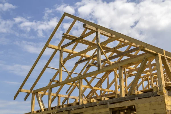 New wooden ecological house from natural materials under construction. Close-up detail of attic roof frame against clear sky. Building, roofing, construction and renovation concept.