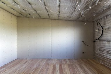 Büyük boş oda altında inşaat ve yenileme ile gümüş alüminyum folyo duvarlar ve tavan, elektrik telleri çıktı, meşe zemin ve duvar. Profesyonel yeniden yapılanma ve izolasyon kavramı.