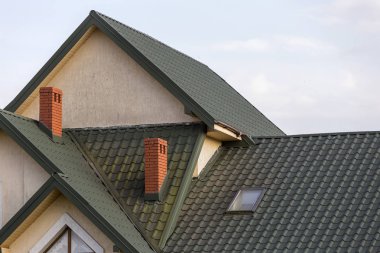 Yakın çekim yeşil çatı shingled, yüksek tuğla kırmızısı bacalar ve sıva duvarlar ile yeni modern ev üst detayını. Profesyonel olarak yapılan bina ve inşaat işi, gayrimenkul, sözleşme kavramı.