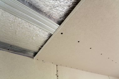 Yakın çekim alt görünümü altında inşaat ve yenileme gümüş alüminyum izolasyon folyo ve alçıpan ile bitmemiş Oda duvarlar ve tavan. Profesyonel iş ve yenileme kavramı.