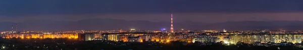 広いパノラマ 近代的な観光イヴァーノ フランキーウシク市 ウクライナの空中夜景 背の高い建物 高いテレビ塔 カルパティア山脈の背景に緑豊かな郊外の明るいライトのシーン — ストック写真