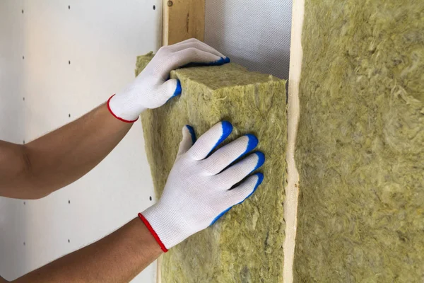 用白色手套将工人的手特写在中空的岩石羊毛绝缘的工作人员在木框架为未来的墙壁的冷屏障 舒适温馨的家居 建筑和装修理念 — 图库照片