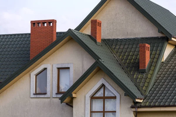 緑の屋根をふかれた屋根 高いレンガの煙突 漆喰の壁 プラスチック屋根裏窓と大きな現代の高価な住宅のトップ 専門的に行う工事 不動産販売コンセプト — ストック写真