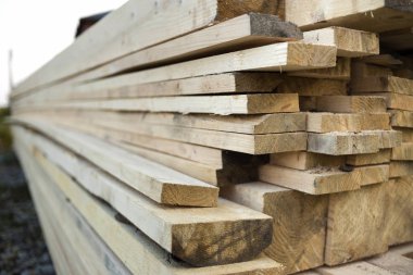 Parlak güneş tarafından yaktı doğal kahverengi düzensiz kaba ahşap Komiteler Kazıklı yığını Close-up. Endüstriyel ahşap marangozluk, bina, onarım ve mobilya, İnşaat için kereste malzeme için.