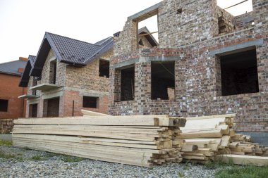 İnşaat ve çakıl yığını ve panoları önünde yığını altında gelecekteki yazlık yeni büyük tuğla ev kahverengi shingled çatı ile bitmiş değil. İnşaat ve gayrimenkul yatırım kavramı.