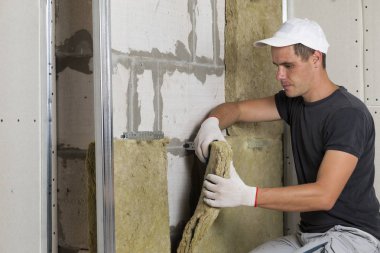 Taşyünü yalıtım için soğuk bariyer için gelecekteki ev duvarları ahşap çerçeve içinde iş koruyucu eldivenler işçi. Rahat sıcak ev, ekonomi, inşaat ve tadilat kavramı