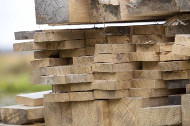 Parlak güneş tarafından yaktı doğal kahverengi düzensiz kaba ahşap Komiteler Kazıklı yığını Close-up. Endüstriyel ahşap marangozluk, bina, onarım ve mobilya, İnşaat için kereste malzeme için.