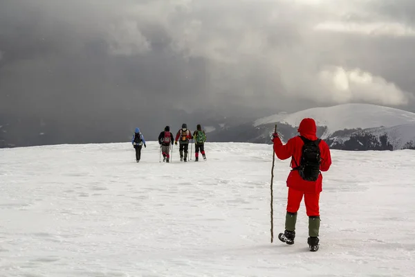 Turistas Excursionistas Invierno Montañas Cubiertas Nieve Nubes Dramáticas Cielo —  Fotos de Stock