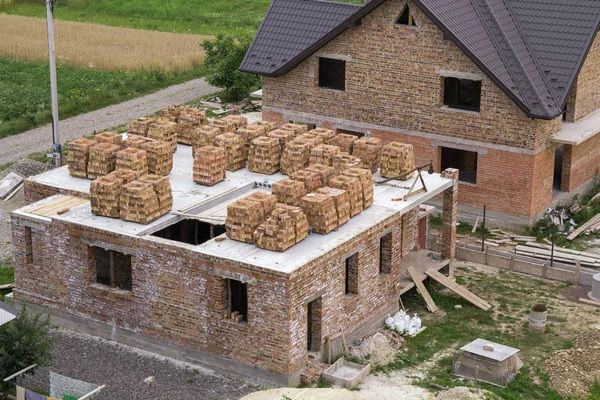 Yeşil alan sitede binanın havadan görünümü. Tuğla bodrum katında gelecekteki evi ve kahverengi shingled çatı ile bitmedi yeni büyük tuğla ev. İnşaat ve gayrimenkul yatırım kavramı.
