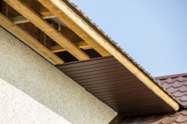 Alt görünümü ayrıntılı yeni modern ev yazlık köşesinde sıva duvarlar ile çatı ve bitmemiş siding yükleme açık mavi gökyüzü kopya alan arka plan üzerinde kahverengi shingled. Emlak kavramı.