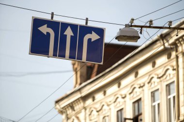 Yol işaret Close-up ulaşım hareket yönünde gösterilen mavi arka plan üzerinde üç beyaz oklarla Caddesi üzerinde yüksek lamba yakın tramvay hattına bağlı. Sipariş, seçim ve kuralları kavramı.