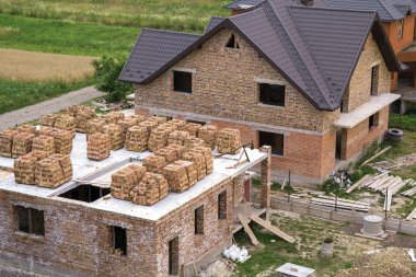 Yeşil alan sitede binanın havadan görünümü. Tuğla bodrum katında gelecekteki evi ve kahverengi shingled çatı ile bitmedi yeni büyük tuğla ev. İnşaat ve gayrimenkul yatırım kavramı.