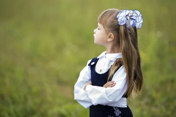 轮廓肖像可爱可爱的第一年级女生在学校制服和白色弓长头发与抬起头 闭上眼睛模糊绿色阳光户外复制空间背景 — 图库照片