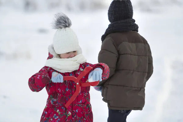 两个可爱的孩子在温暖的衣服与明亮的雪剪辑玩有乐趣做雪球在冬季冷天白色明亮模糊复制空间背景 户外活动 假日游戏 — 图库照片