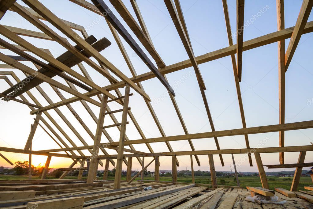 New wooden house under construction. Close-up of attic roof frame against clear sky from inside. Ecological dream home of natural materials. Building, construction and renovation concept.