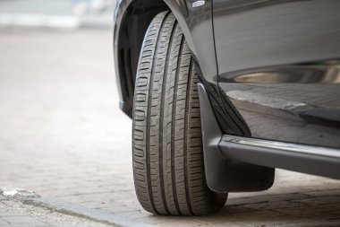 Araba tekerlek yeni siyah kauçuk lastik koruyucu ile hafif bulanık kopya alan arka plan üzerinde ayrıntı bölümü kapatın. Ulaşım, güvenlik, güvenilirlik, modern tasarım konsepti.