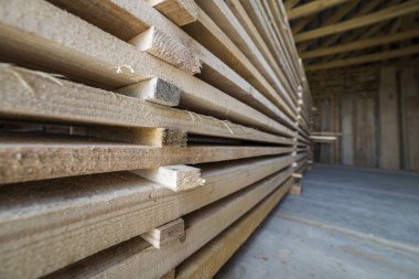 Perspektif görünümünü doğal düzensiz kaba ahşap kurulları uzun yığını içinde tavan arası Oda yapım aşamasında düzgünce Kazıklı. Endüstriyel ahşap marangozluk, yapı, İnşaat için kereste malzeme için.