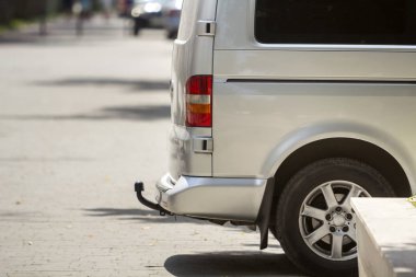 Yakın çekim yan görünümü ayrıntı gümüş yolcu orta boy Lüks Minibüs Van ile römork yaz güneşli şehir sokak kaldırım bulanık siluetleri ile yayalar ve arka planda otomobil park.