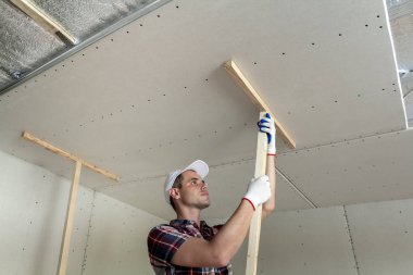 Genç işçi koruma iş eldivenleri ahşap sahipleri drywall için sabitleme metal çerçeve parlak alüminyum folyo ile yalıtımlı tavana askıya. DIY, kendiniz yapın kavramı.