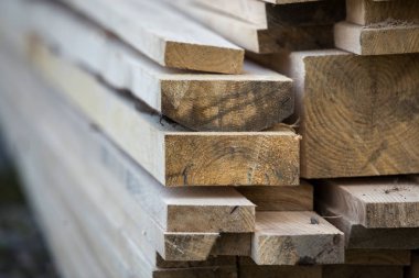 Parlak güneş tarafından yaktı doğal kahverengi düzensiz kaba ahşap Komiteler Kazıklı yığını Close-up. Endüstriyel ahşap marangozluk, bina, onarım ve mobilya, İnşaat için kereste malzeme için.