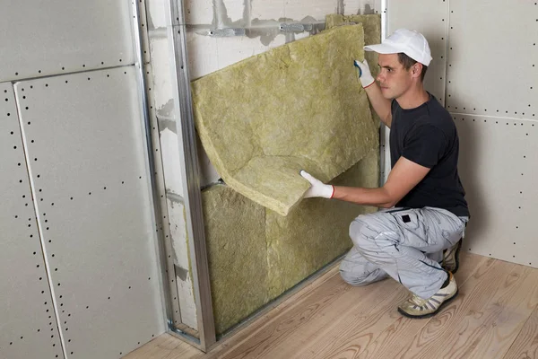 stock image Worker in protective gloves insulating rock wool insulation in wooden frame for future house walls for cold barrier. Comfortable warm home, economy, construction and renovation concept