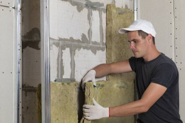 Taşyünü yalıtım için soğuk bariyer için gelecekteki ev duvarları ahşap çerçeve içinde iş koruyucu eldivenler işçi. Rahat sıcak ev, ekonomi, inşaat ve tadilat kavramı