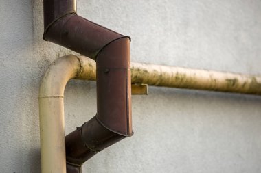 Kirli boyalı sarı doğal gaz ve kahverengi cilt payı yağmur su boruları Beyaz Saray duvara sabitlenmiş yakın çekim detay eski. Güvenlik, tehlike, eski ve modern teknoloji kavramı. Alan arka plan kopyalama.