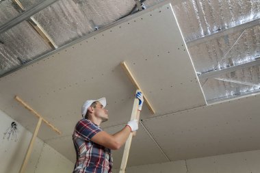 Genç işçi koruma iş eldivenleri ahşap sahipleri drywall için sabitleme metal çerçeve parlak alüminyum folyo ile yalıtımlı tavana askıya. DIY, kendiniz yapın kavramı.