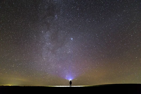 在美丽的深蓝色夏季星空下 头上手电筒站在绿色草地上的人的背影 夜间摄影 美丽的自然概念 宽全景 复制空间背景 — 图库照片