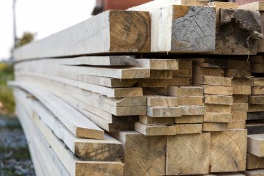 Parlak güneş tarafından yaktı doğal kahverengi düzensiz kaba ahşap Komiteler Kazıklı yığını Close-up. Endüstriyel ahşap marangozluk, bina, onarım ve mobilya, İnşaat için kereste malzeme için.