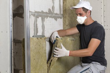 Ahşap çerçeve için soğuk bariyer için gelecekteki ev duvarları taş yünü izolasyon yalıtım Koruyucu solunum maskesi işçi. Rahat sıcak ev, ekonomi, inşaat ve tadilat kavramı