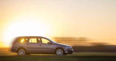 Uzun pozlama gri gümüş araba bulanık parlak turuncu açık gökyüzü günbatımı kopya alan arka plan, hızlı kırsal kesimde devam vurdu. Ulaşım, hızlı, seyahat, Araçlar tasarım konsepti.