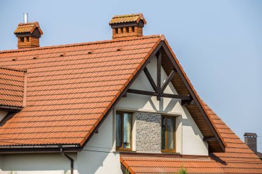 İlk büyük modern pahalı konut ev yazlık shingled dik kahverengi çatısı, yüksek tuğla baca, sıva duvarlar, oluk sistemi ve Plastik tavan windows mavi gökyüzü kopya alan arka plan üzerinde.