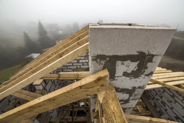 Çatı çerçeve kaba ahşap kereste kirişler ve plakalar üstten görünüm duvar içi boş köpük yalıtım bloklar kırsal manzara arka plan üzerinde yapılmış. Bina, çatı kaplama, inşaat ve yenileme kavramı.