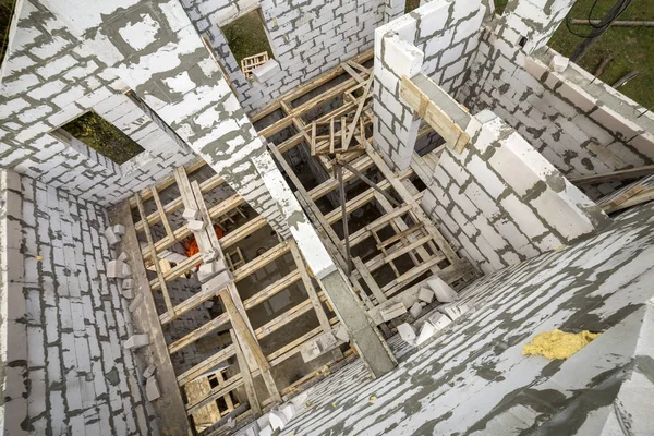 Yukarıdan gelecekteki multi depolanan yazlık enerji tasarrufu büyük beyaz içi boş köpük yalıtım blokları ve geçici ahşap iskele çerçeve görüntüleyin. İnşaat duvar, modern teknoloji kavramı.