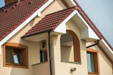 Büyük modern pahalı konut aile yazlık kahverengi çatı shingled, tuğla baca, sıva ile üst ayrıntı açık mavi gökyüzü arka plan üzerinde duvarlar. Gayrimenkul yatırım, rahat konut kavramı.