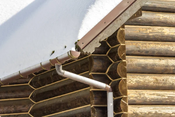 特写镜头的新木温暖的生态小屋屋顶覆盖着雪与钢排水沟雨系统 专业的建筑和排水管安装和连接概念 — 图库照片