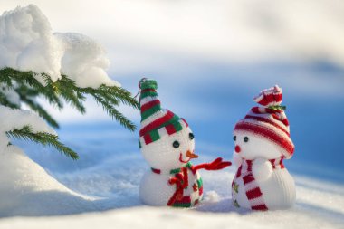 İki küçük komik oyuncak bebek kardan adam örgü şapkalı ve eşarplı açık havada açık havada açık mavi ve beyaz fotokopi arkaplanda. Mutlu yıllar ve Mutlu Noeller tebrik kartı.