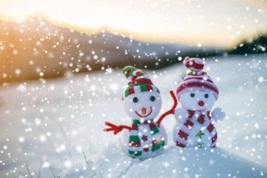 İki küçük komik oyuncaklar kardan adam örme şapka içinde bebek ve arka plan açık havada üzerinde bulanık dağlar derin karda eşarp manzara. Mutlu yeni yıl ve mutlu Noeller tebrik kartı Tema.