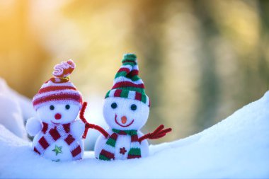 İki küçük komik oyuncak bebek kardan adam örgü şapkalı ve eşarplı açık havada açık havada açık mavi ve beyaz fotokopi arkaplanda. Mutlu yıllar ve Mutlu Noeller tebrik kartı.